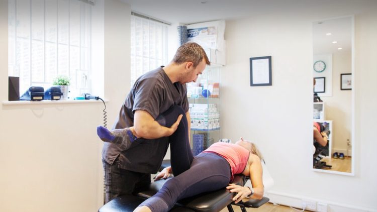 Toby Wragg treating a patient lying face down on a treatment table in the ground floor room.